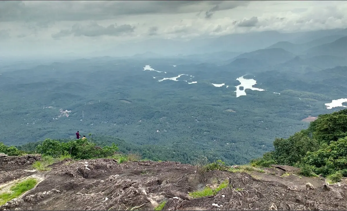 Vayalada viewpoint: panoramic view of lush green hills, valleys, and rivers near JKR Gardens resort, Kerala. Ideal for trekking, nature photography, and scenic relaxation. No visible text.