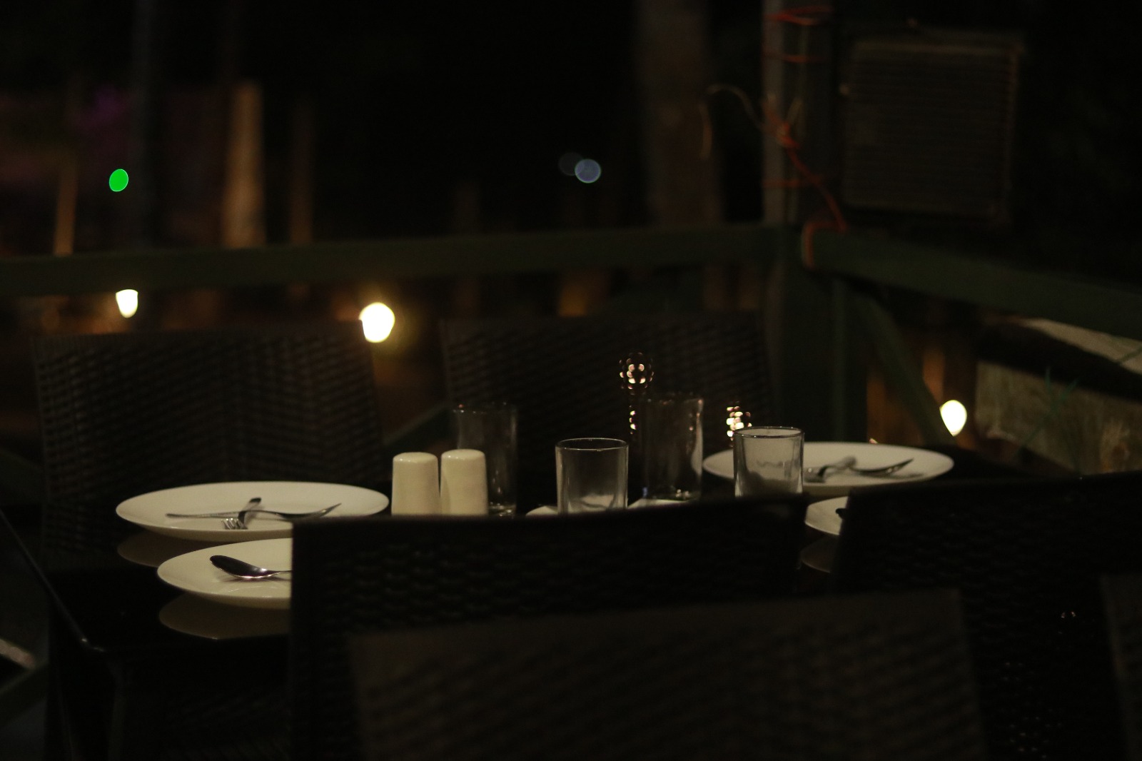 Spacious modern hotel room at JKR Gardens featuring a king-size bed with crisp white linens and a teal runner, wooden furniture, and floor-to-ceiling curtains allowing natural daylight. The room includes a tiled floor, yellow accent wall, air conditioning, and a window overlooking lush green trees, creating a peaceful and inviting atmosphere ideal for relaxation. No visible text.