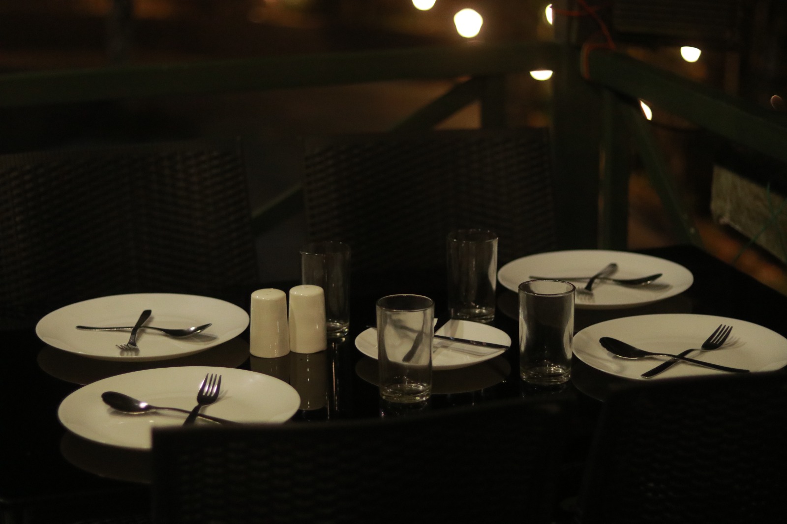 Spacious modern hotel room at JKR Gardens featuring a king-size bed with crisp white linens and a teal runner, wooden furniture, and floor-to-ceiling curtains allowing natural daylight. The room includes a tiled floor, yellow accent wall, air conditioning, and a window overlooking lush green trees, creating a peaceful and inviting atmosphere ideal for relaxation. No visible text.