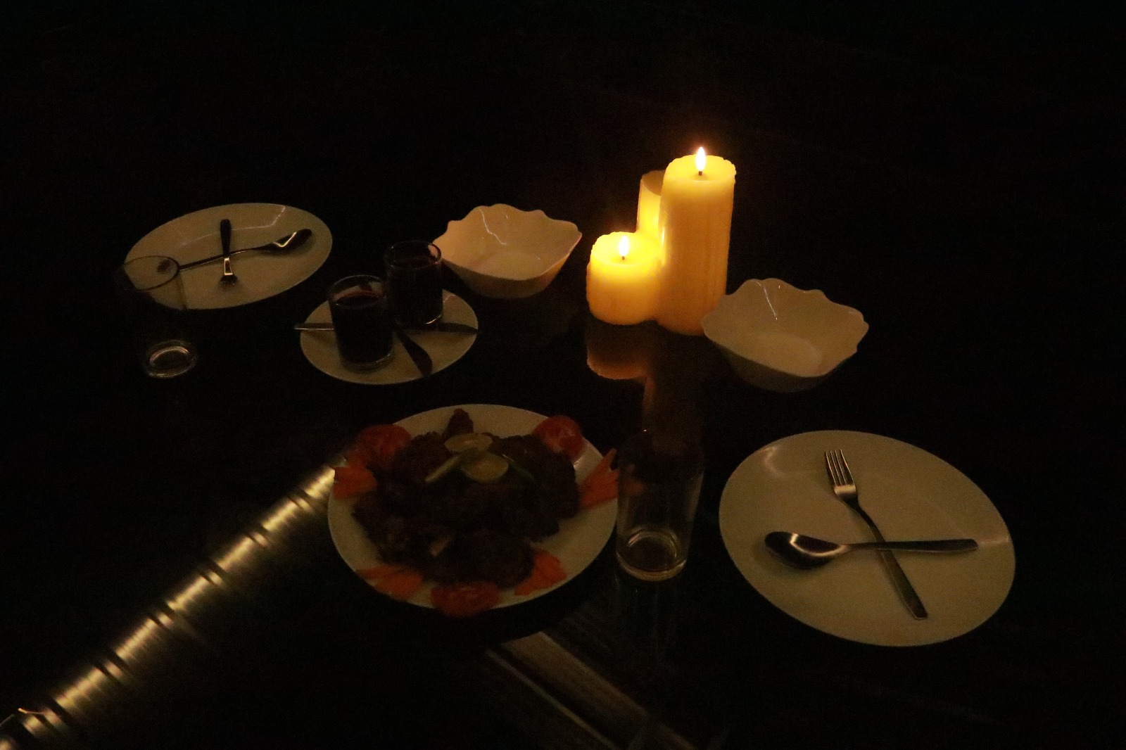 Spacious modern hotel room at JKR Gardens featuring a king-size bed with crisp white linens and a teal runner, wooden furniture, and floor-to-ceiling curtains allowing natural daylight. The room includes a tiled floor, yellow accent wall, air conditioning, and a window overlooking lush green trees, creating a peaceful and inviting atmosphere ideal for relaxation. No visible text.