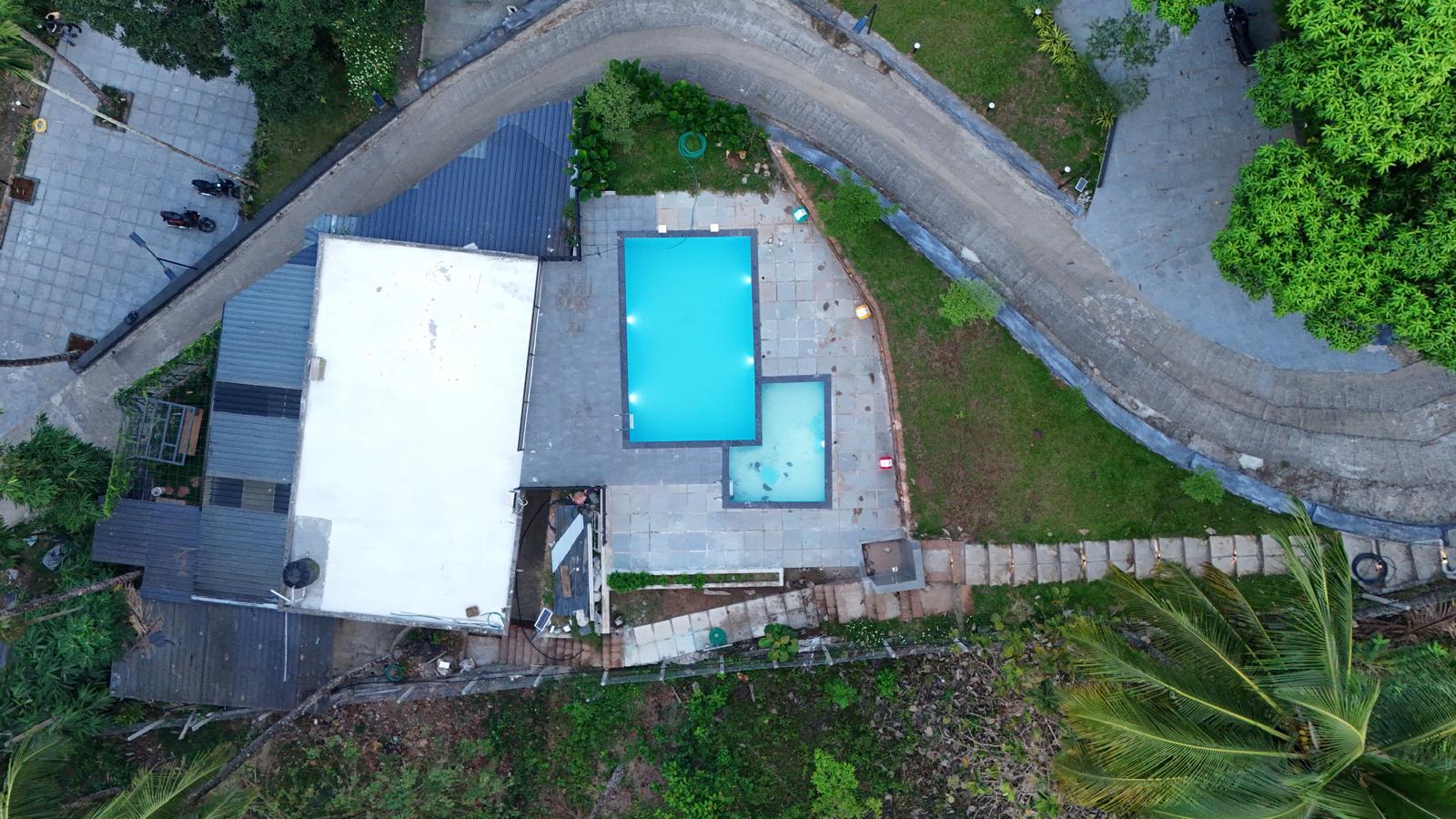 Scenic view of Vayalada hilltop with lush green landscape, mist rolling over the hills, and a clear sky above. The environment is tranquil and expansive, evoking a sense of peace and natural beauty. No visible text.