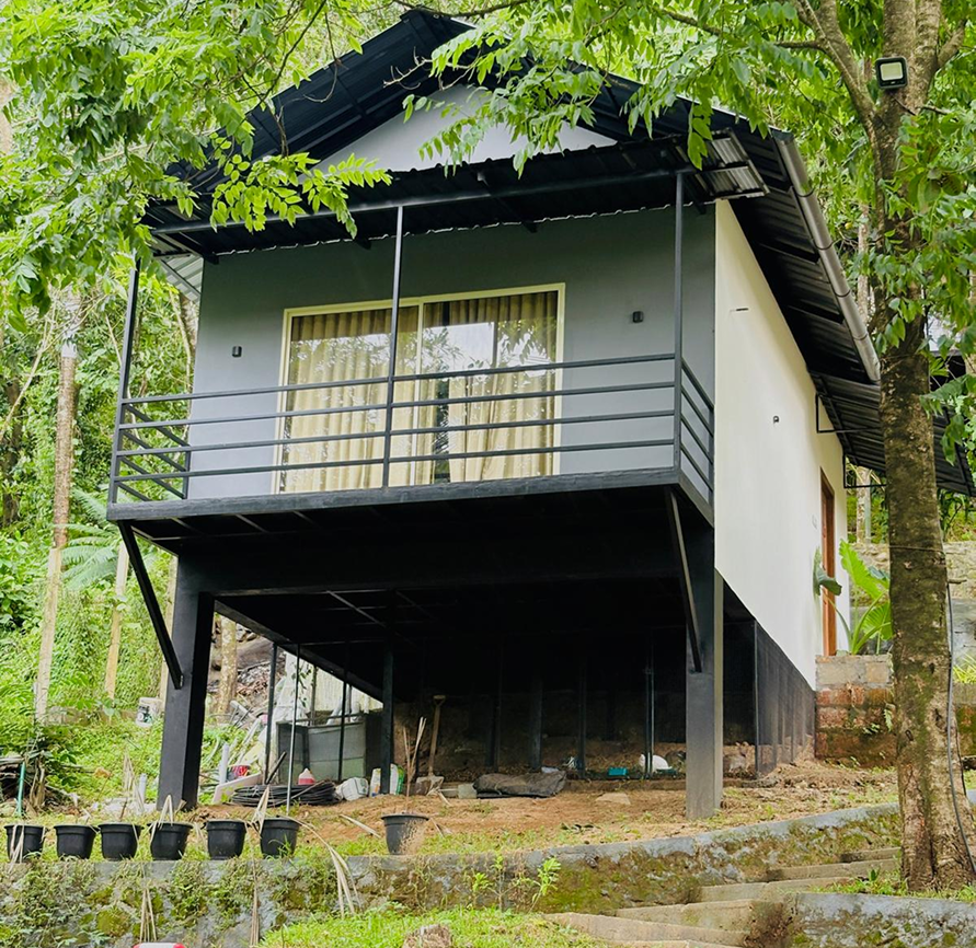 Two friendly resort staff members at a reception desk smiling and assisting a guest, with lush greenery visible through large windows in the background. The environment feels welcoming and professional. No visible text in the image.