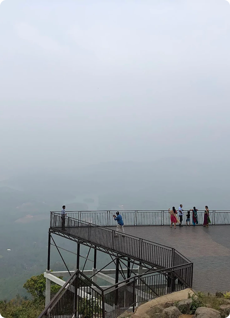 Lounge area with curved blue and orange seating and bean bags facing a large projection screen showing a Crash Bandicoot video game menu. Pink accent lighting streams from tall windows, creating a vibrant, playful environment ideal for socializing or gaming. No visible text. The mood is energetic and inviting.