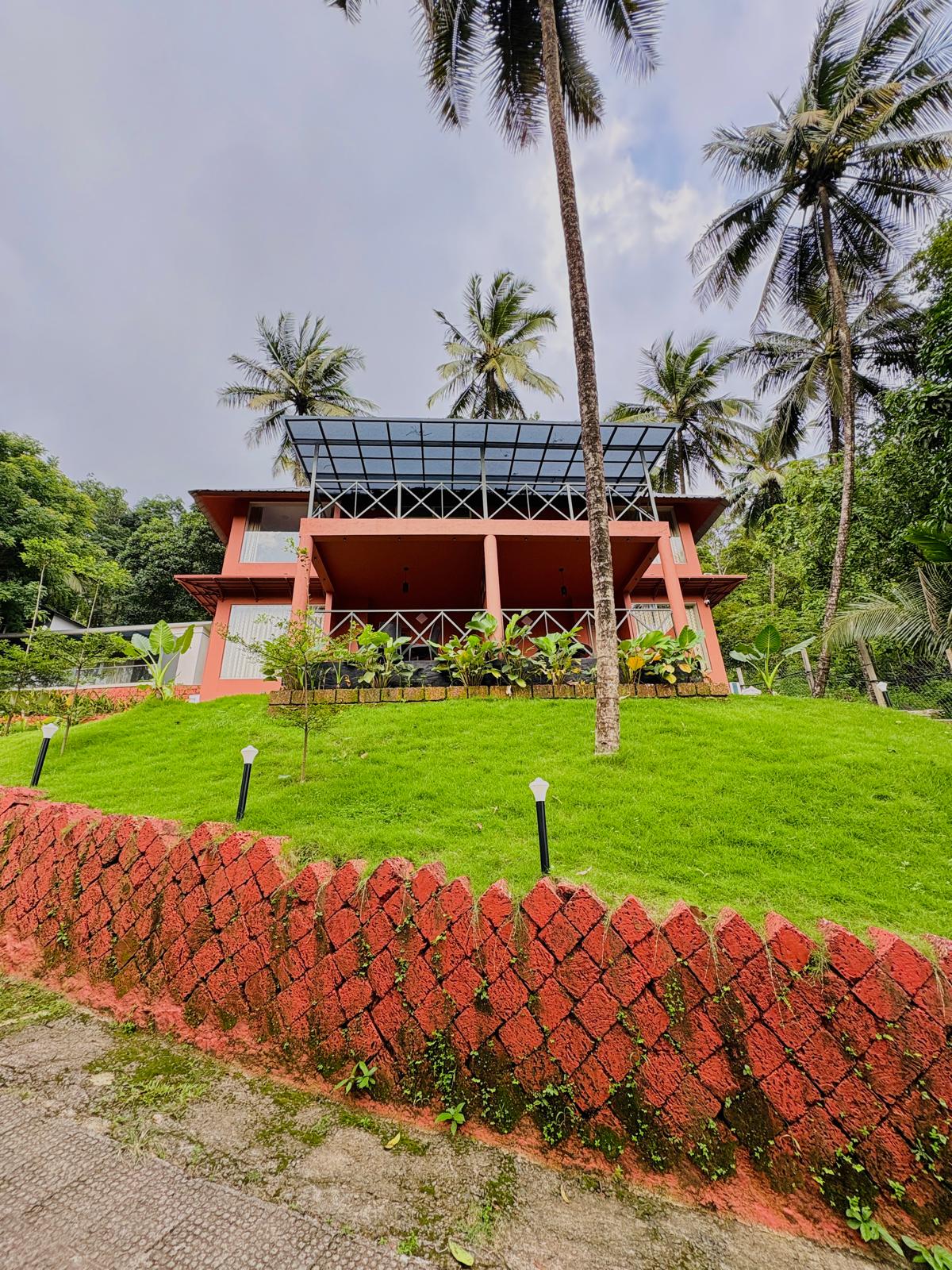 Modern lounge area with curved blue and orange seating, bean bags, and a large projection screen displaying a video game menu. Pink accent lighting streams from tall windows, creating a vibrant, playful environment ideal for socializing or gaming. No visible text. The mood is energetic and inviting.