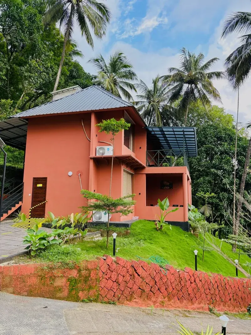 Pillar house exterior surrounded by coconut palms in Vayalada