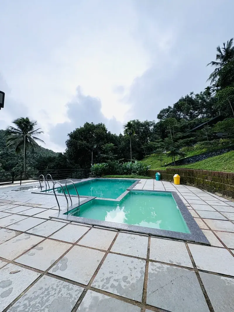 Swimming pool at Vayalada Gardens Resort with hills behind
