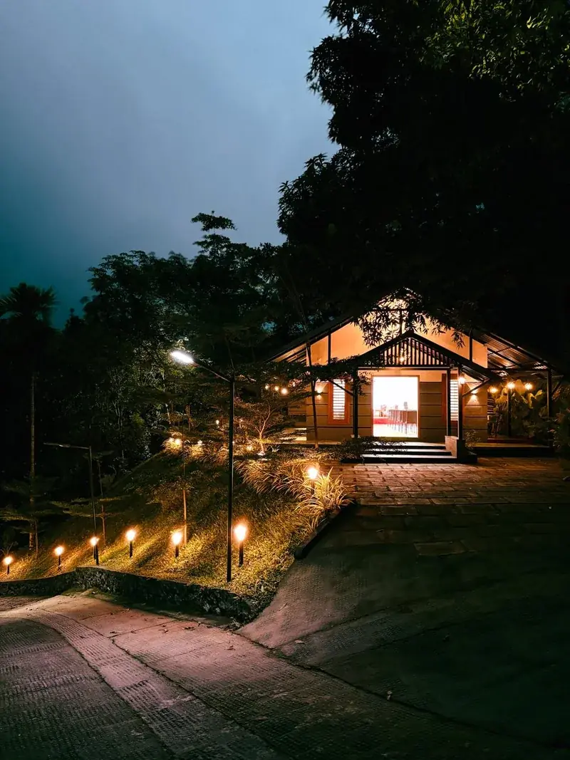 Resort pavilion glowing at dusk in Vayalada, Kerala